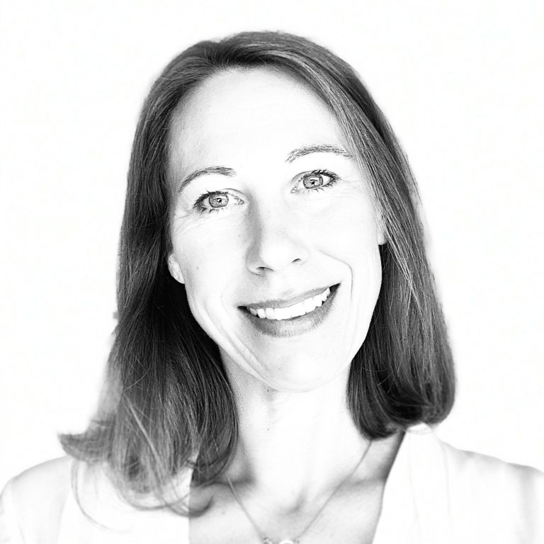 Lächelnde Frau mit langen Haaren vor hellem Hintergrund.